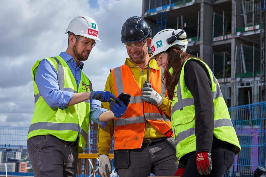 3 construction workers looking at a phone